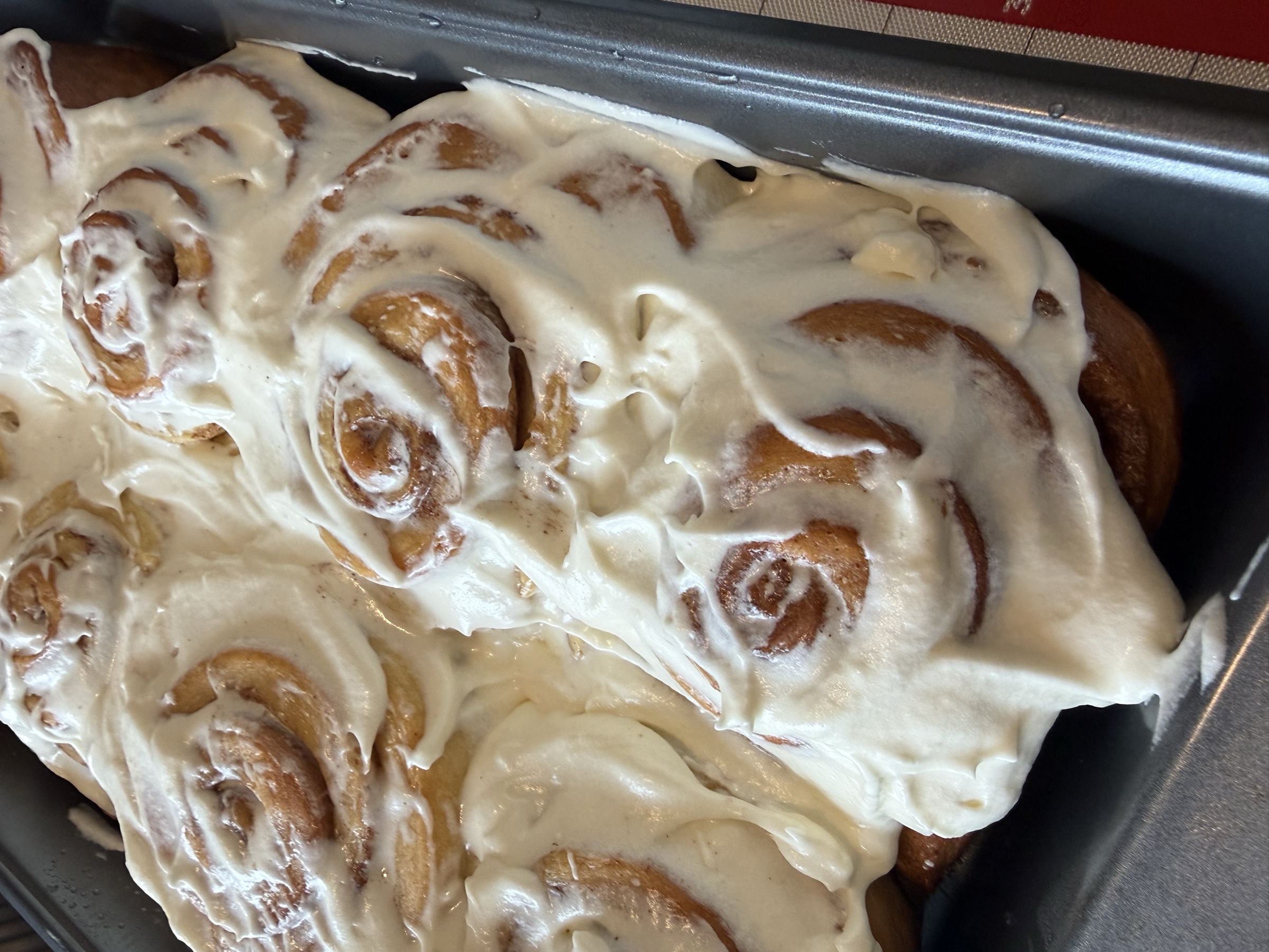 Glaze cinnamon rolls with smooth frosting and browned edges